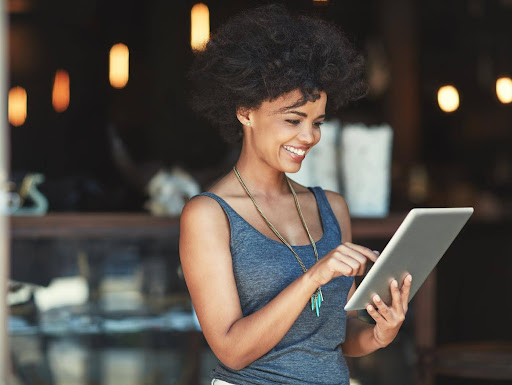 Smiling woman using a tablet outside a café or store, representing confident website users and the importance of an engaging homepage experience.