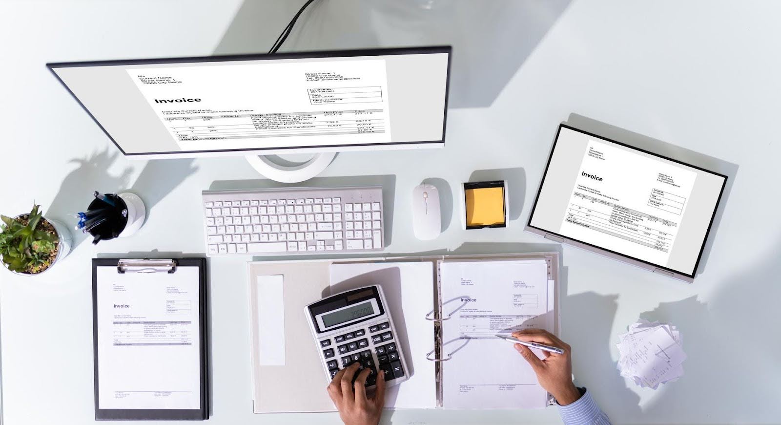 Person using a calculator and reviewing paper invoices, with digital invoices displayed on a computer and tablet—illustrating the contrast between manual and cloud-based bookkeeping systems.