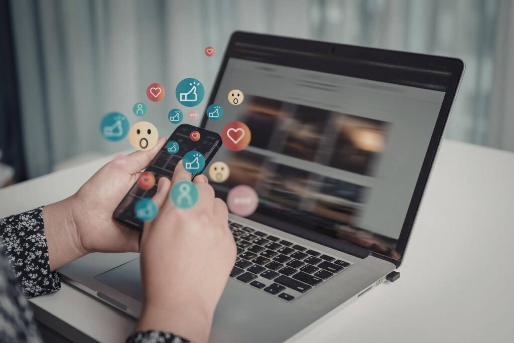 Techfellow analyzing Posting strategy on social media, shown by a smartphone and laptop with engagement icons, highlighting how strategic posting turns content into measurable business profit.