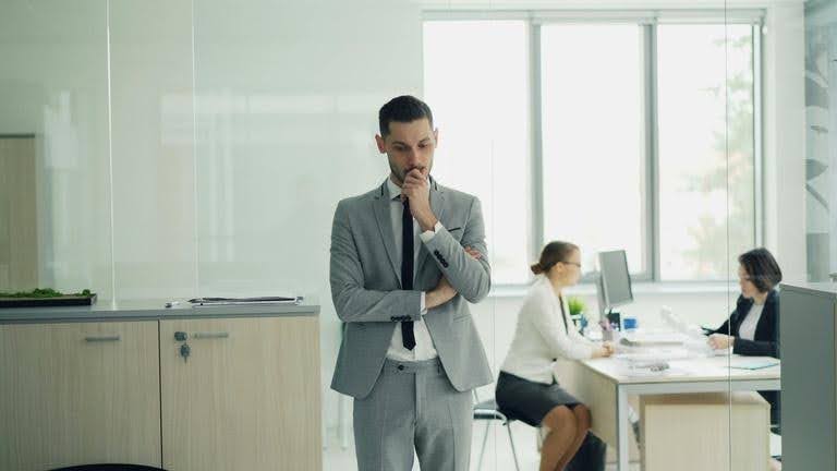 Business owner considering everyday decisions while employees work in the background at Techfellow.