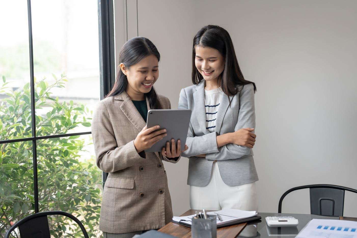 Two business professionals reviewing information on a tablet, highlighting how digital marketing and effective customer follow-ups help businesses retain potential customers.