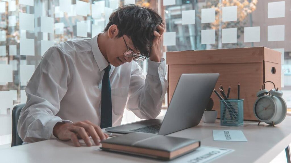 Stressed small business owner reviewing work on a laptop, highlighting the challenges of converting qualified leads into paying customers and improving sales performance.